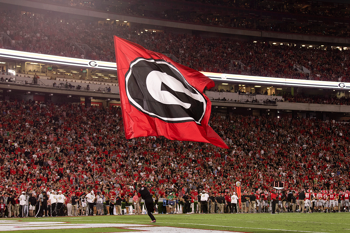 photo of UGA cheerleader running the super G flag onto the football field