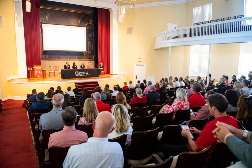 Parents sitting in the UGA chapel watching a panel of students on stage speaking