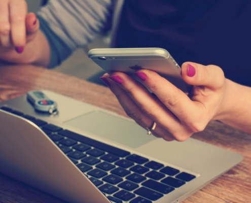 Phone in hand by computer